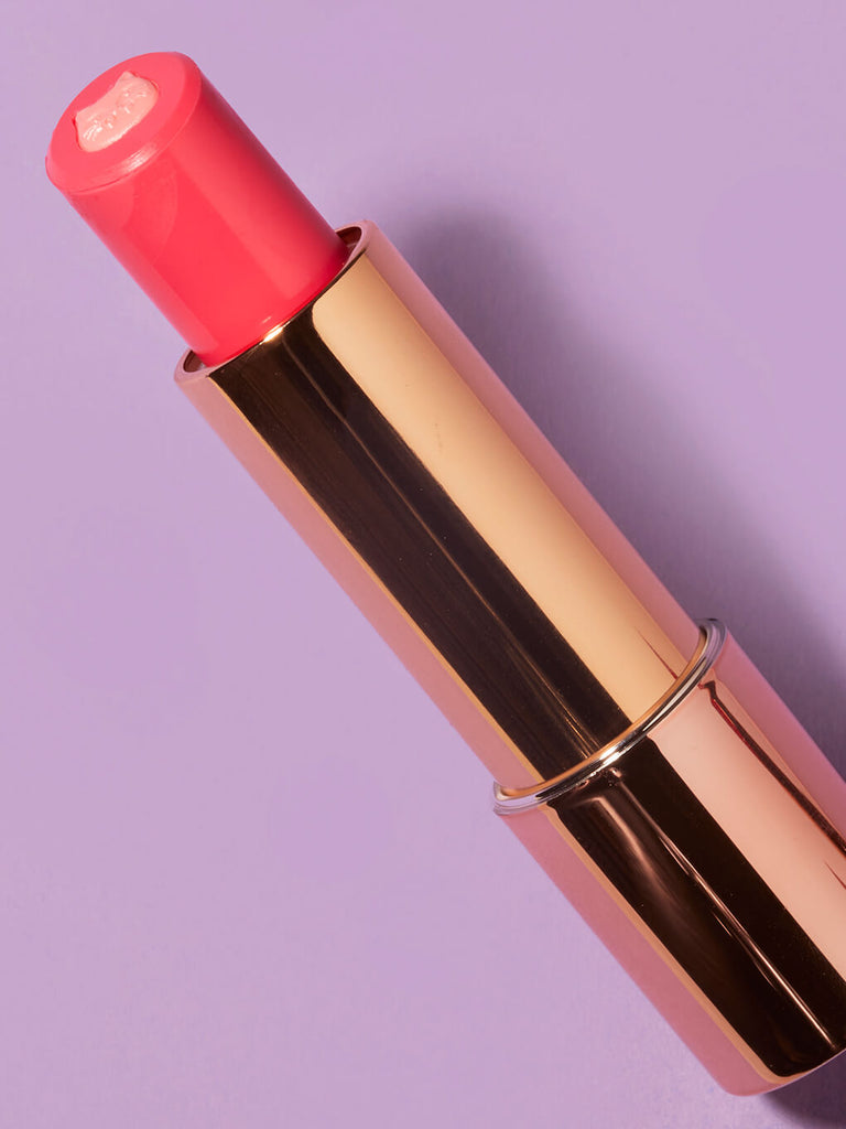 purrincess -- close up of purrfect pout sheer lipstick flat lay on purple background