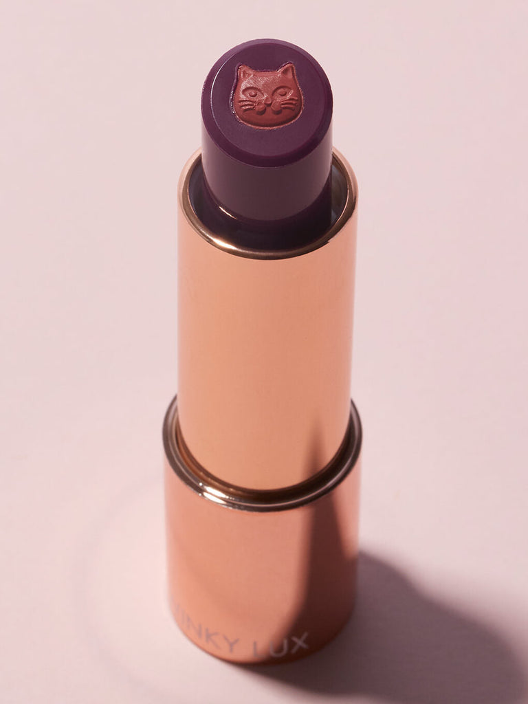 frisky -- purrfect pout sheer lipstick standing up no cap on pink background