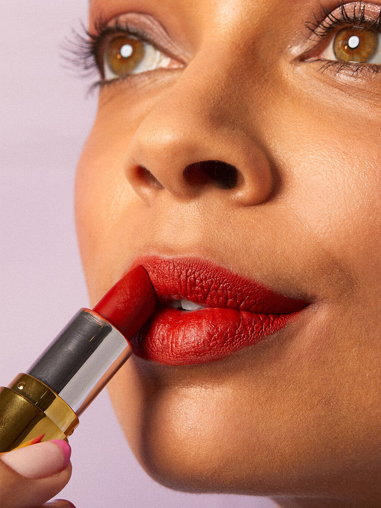 dirty love -- close up of brunette model applying red matte lip velour lipstick