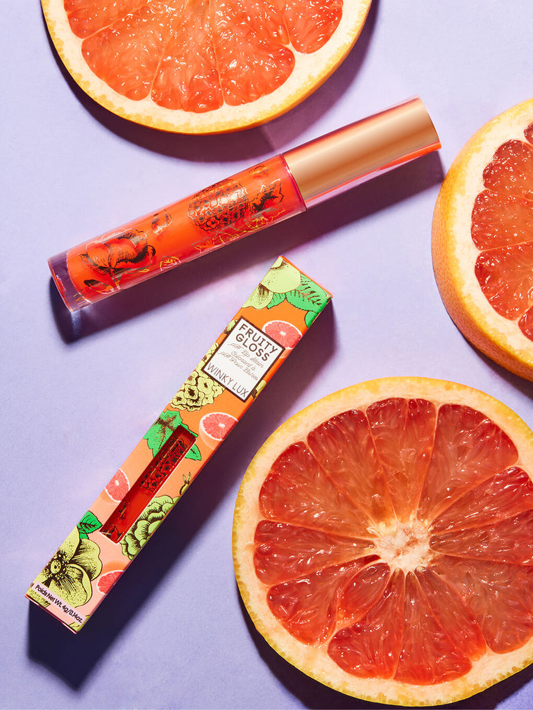 grapefruit -- fruity ph lip gloss flat lay on purple background surrounded by grapefruit slices
