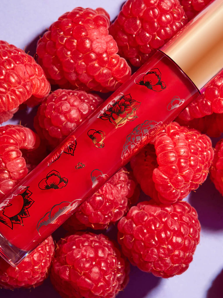 raspberry -- fruity ph gloss lying on a bed of raspberries