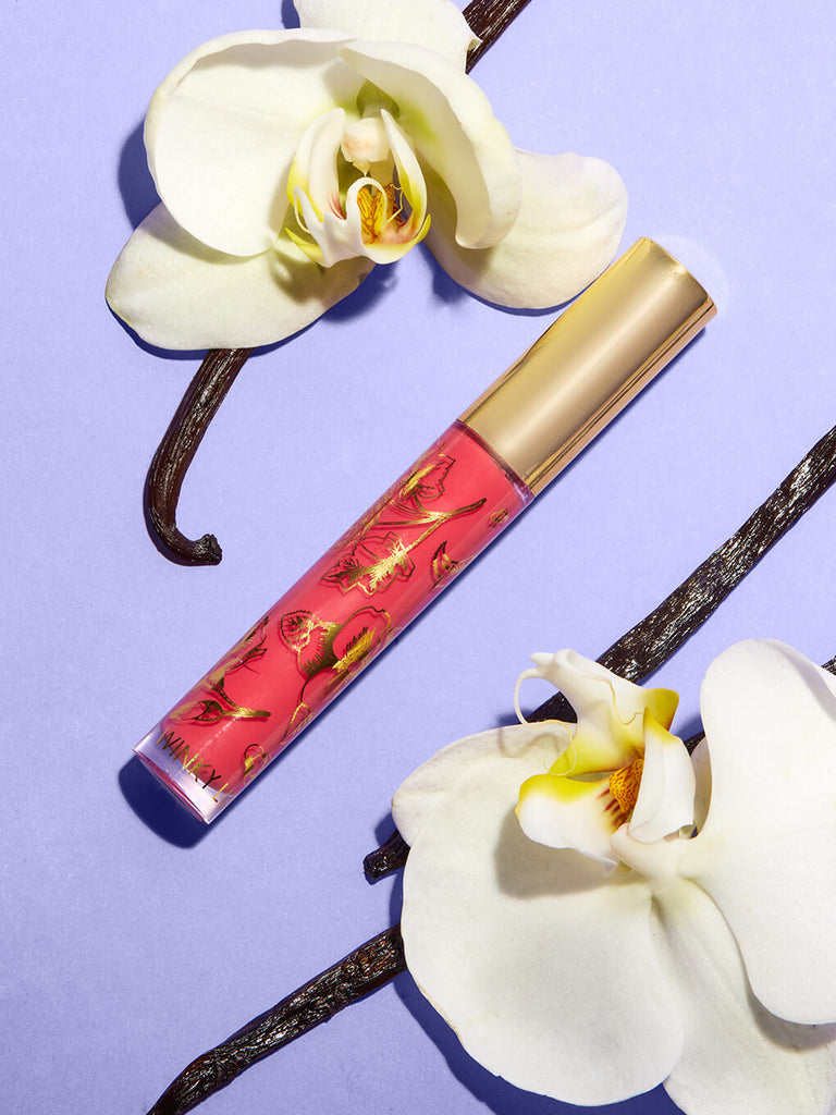 Juicy -- glossy boss lip gloss flat lay on purple background with orchids surrounding