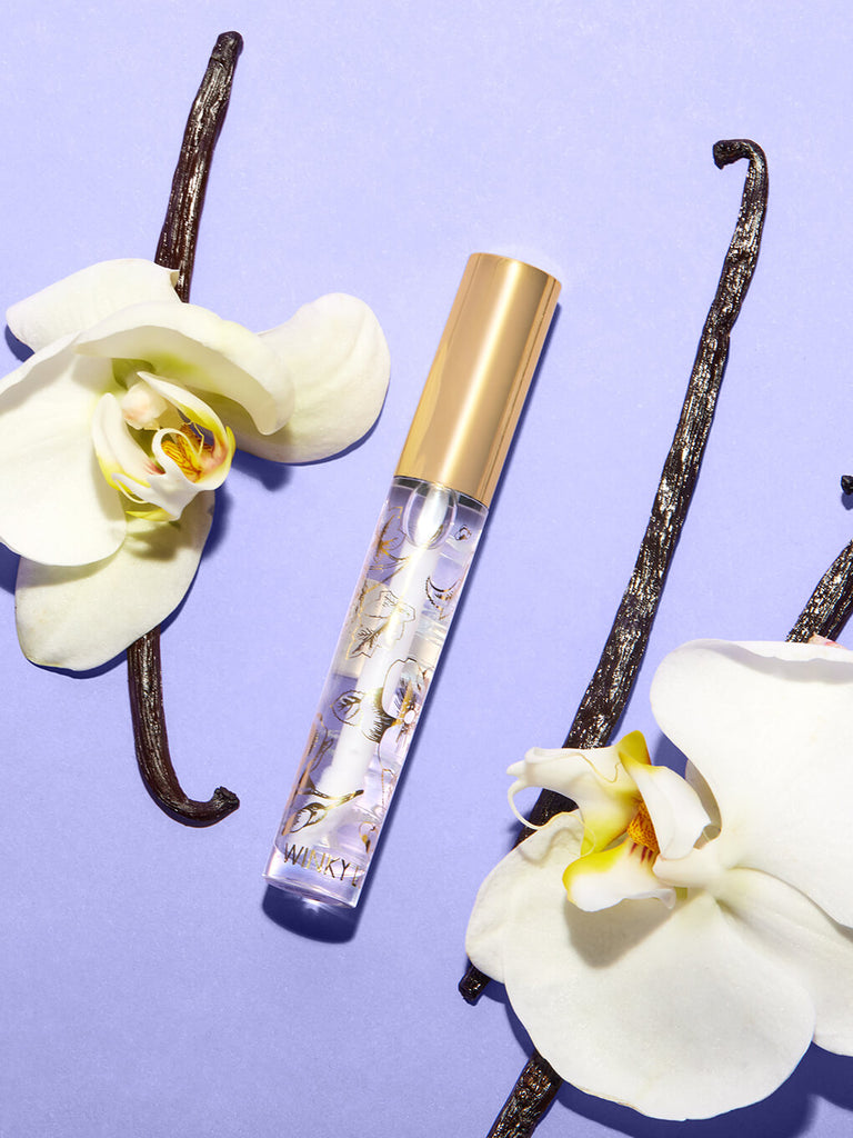 On The Rocks -- glossy boss lip gloss flat lay on purple background surrounded by orchids