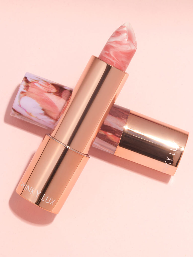 Dreamy -- marbleous hydrating lip balm laying on top of another on pink background