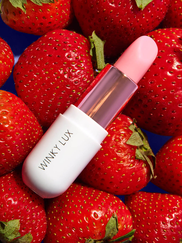 strawberry -- matcha lip balm laying down on strawberries 
