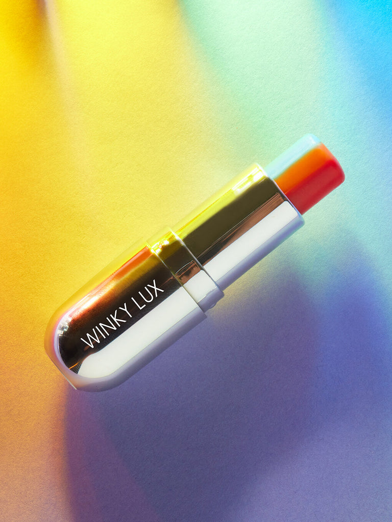flat lay of rainbow tinted ph lip balm on colorful background
