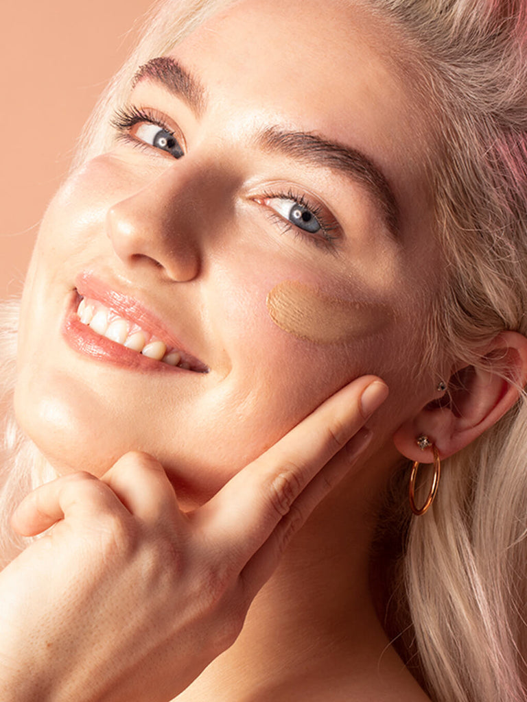 Fair -- close up of blonde model smiling with tinted moisturizer spf 30 on her cheek bone