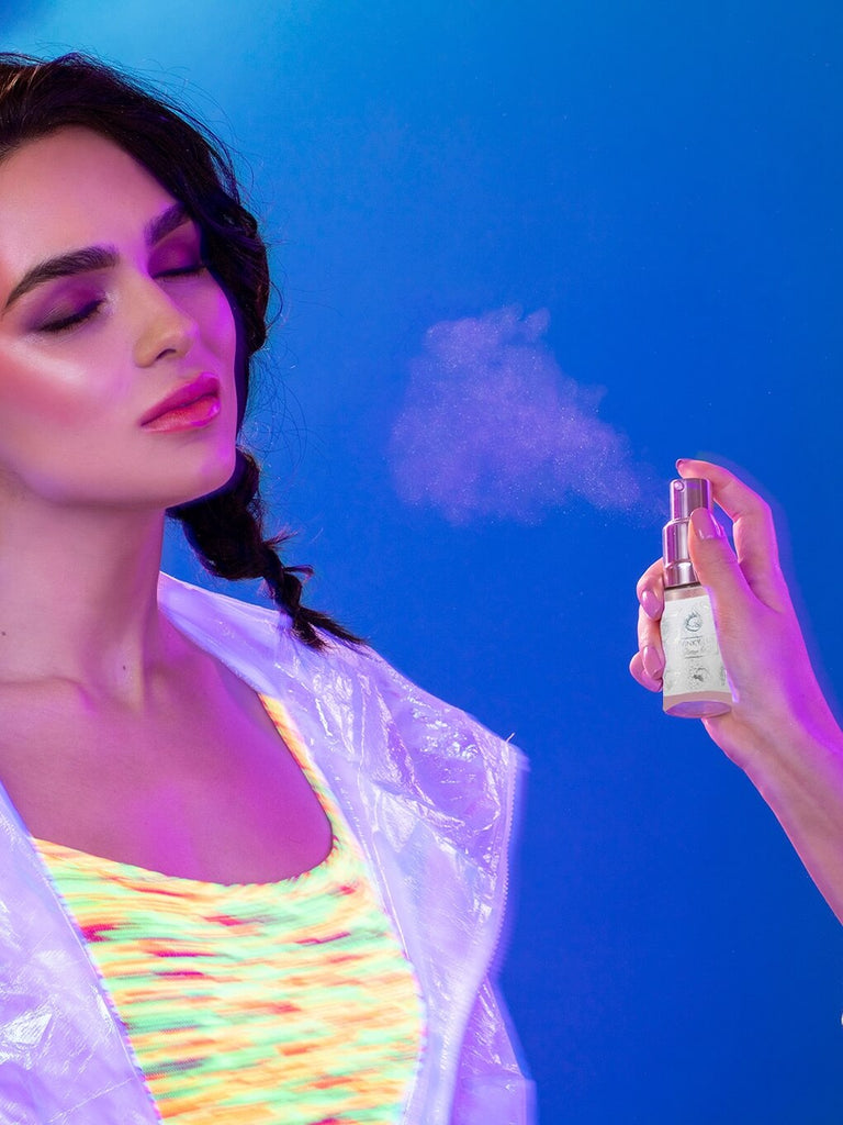 spraying glitter puff body glitter towards model on blue background