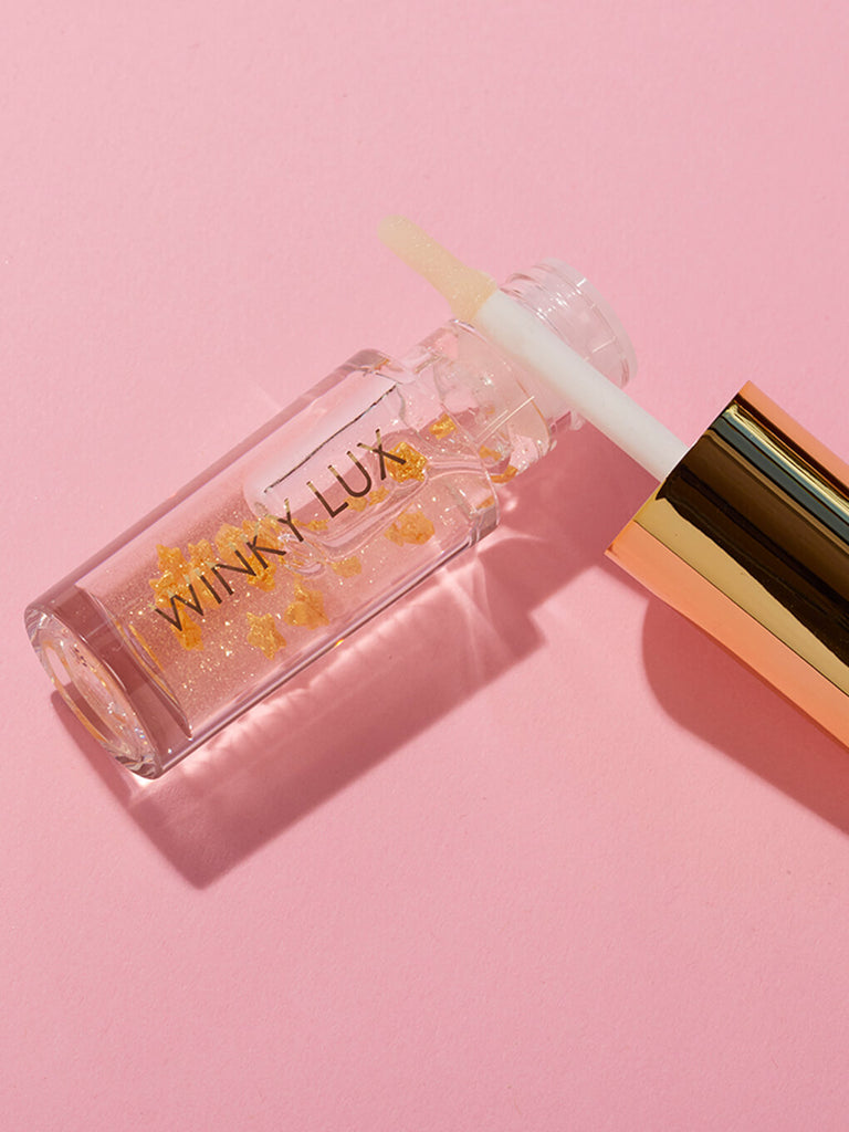 in the stars nourishing lip oil applicator resting on top of bottle on pink background