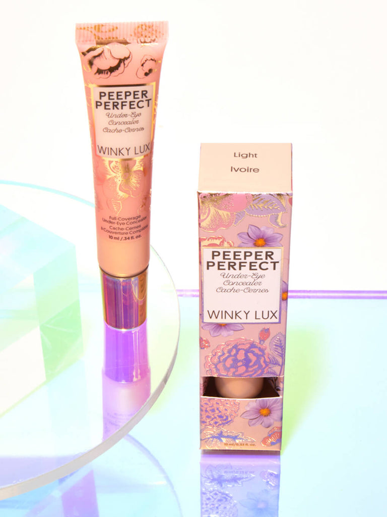 Light -- peeper perfect under eye concealer next to box with shiny props