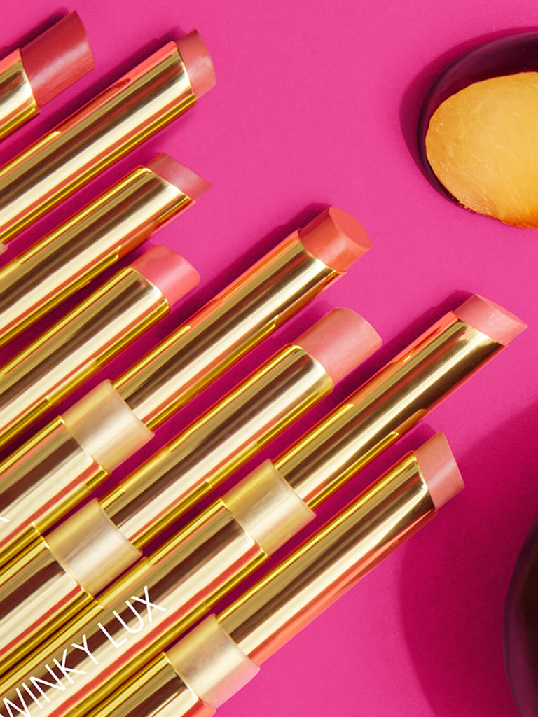 first crush -- 8 shades of skinny plump demi matte plumping lipstick flat lay next to plums