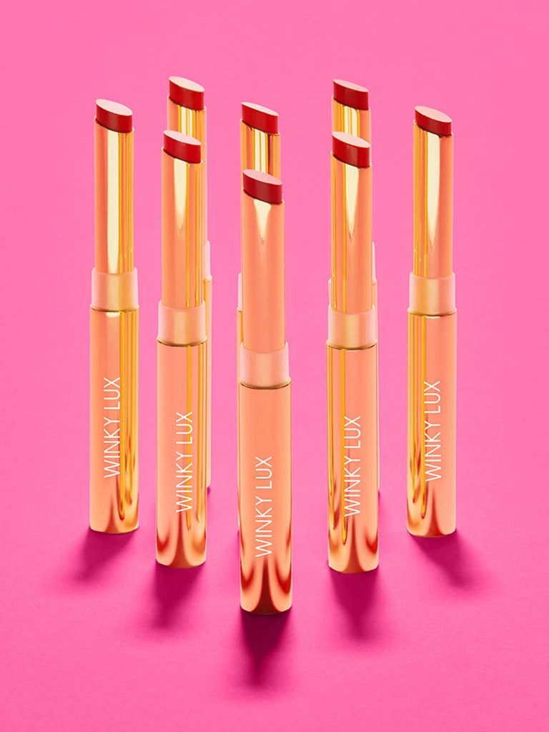 rom com -- 8 shades of skinny plump demi matte plumping lipstick standing on hot pink surface