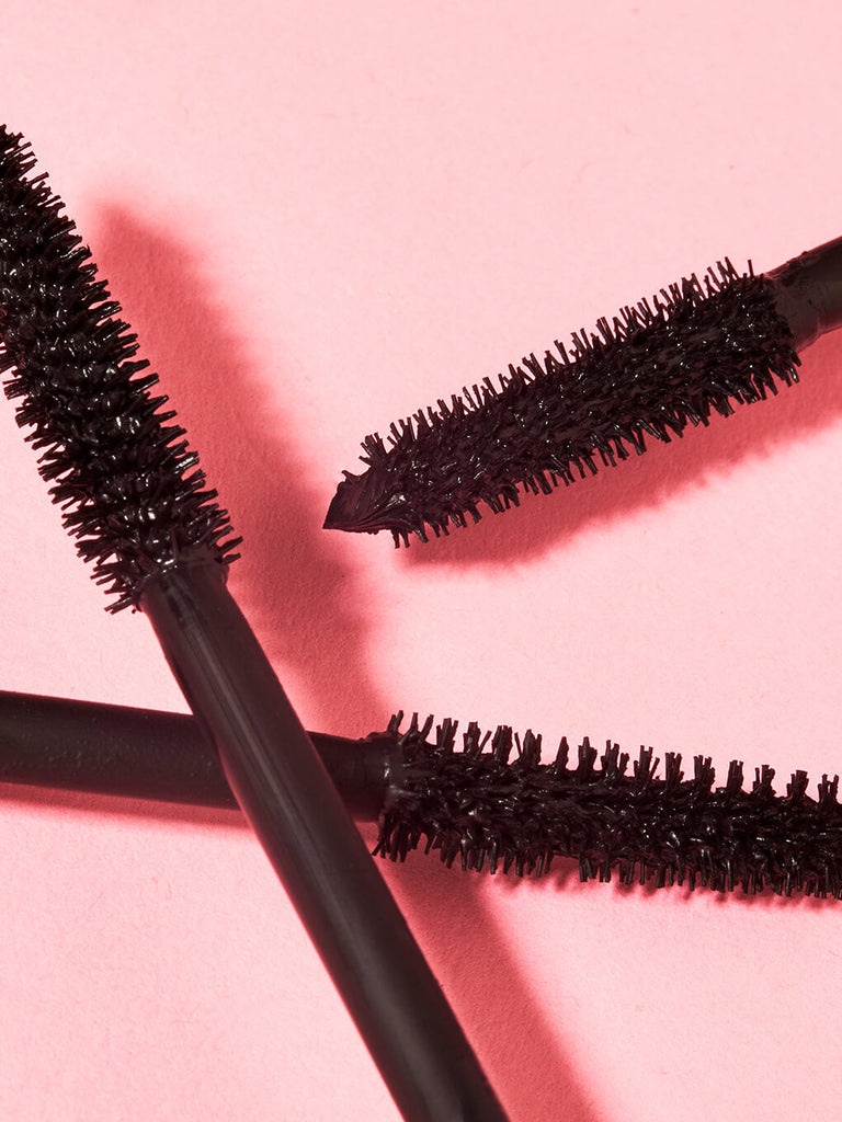 close up of so extra volumizing mascara brushes interlaced on light pink background