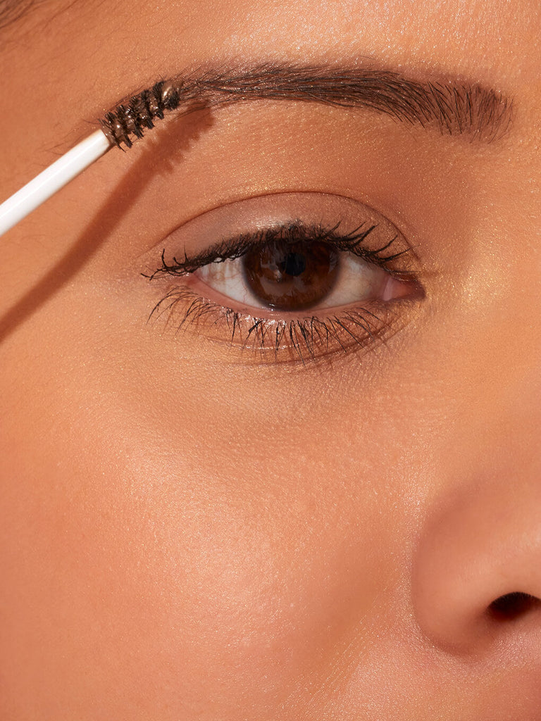 brown -- close up of brunette model applying unibrow tinted brow gel