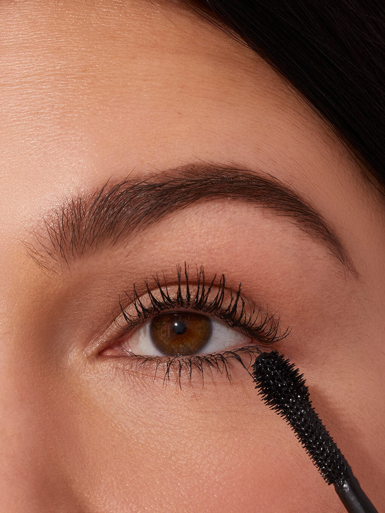 close up of brunette model applying extravalash mascara to lashes