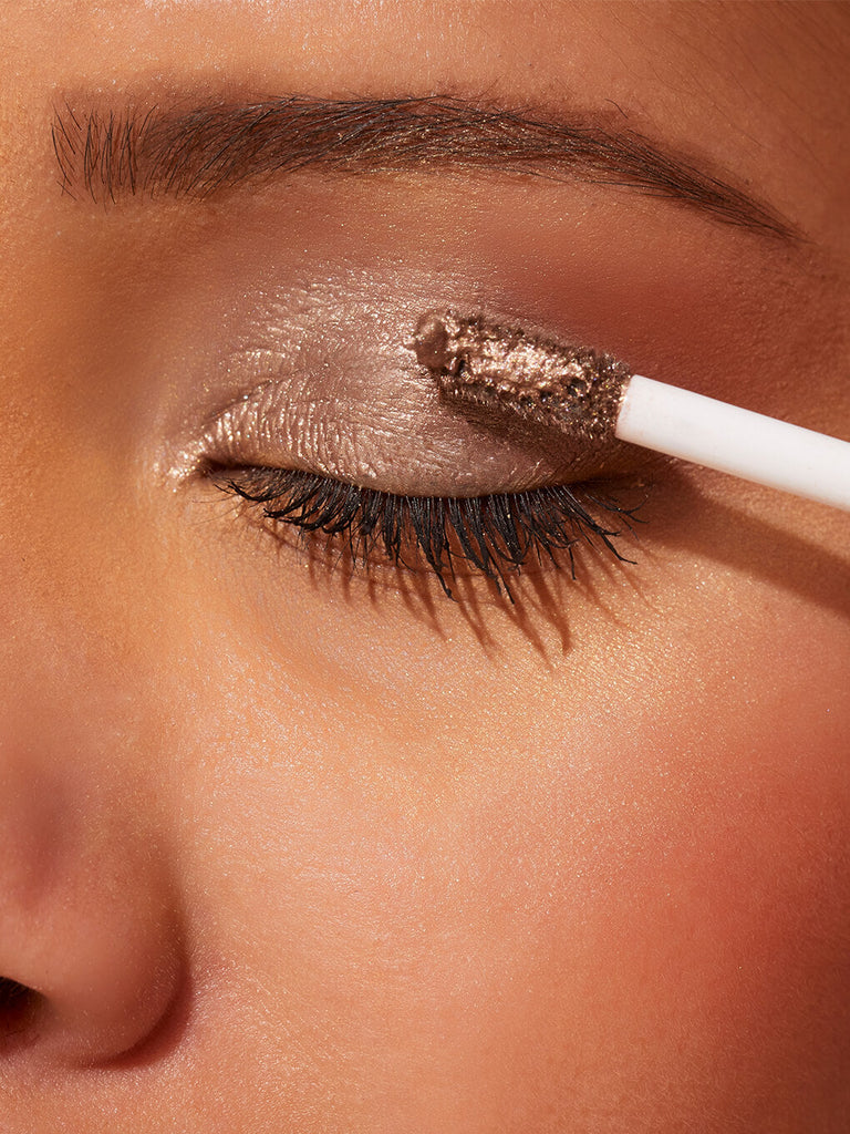 rolly -- close up of brunette model applying chadelier shimmer shadow