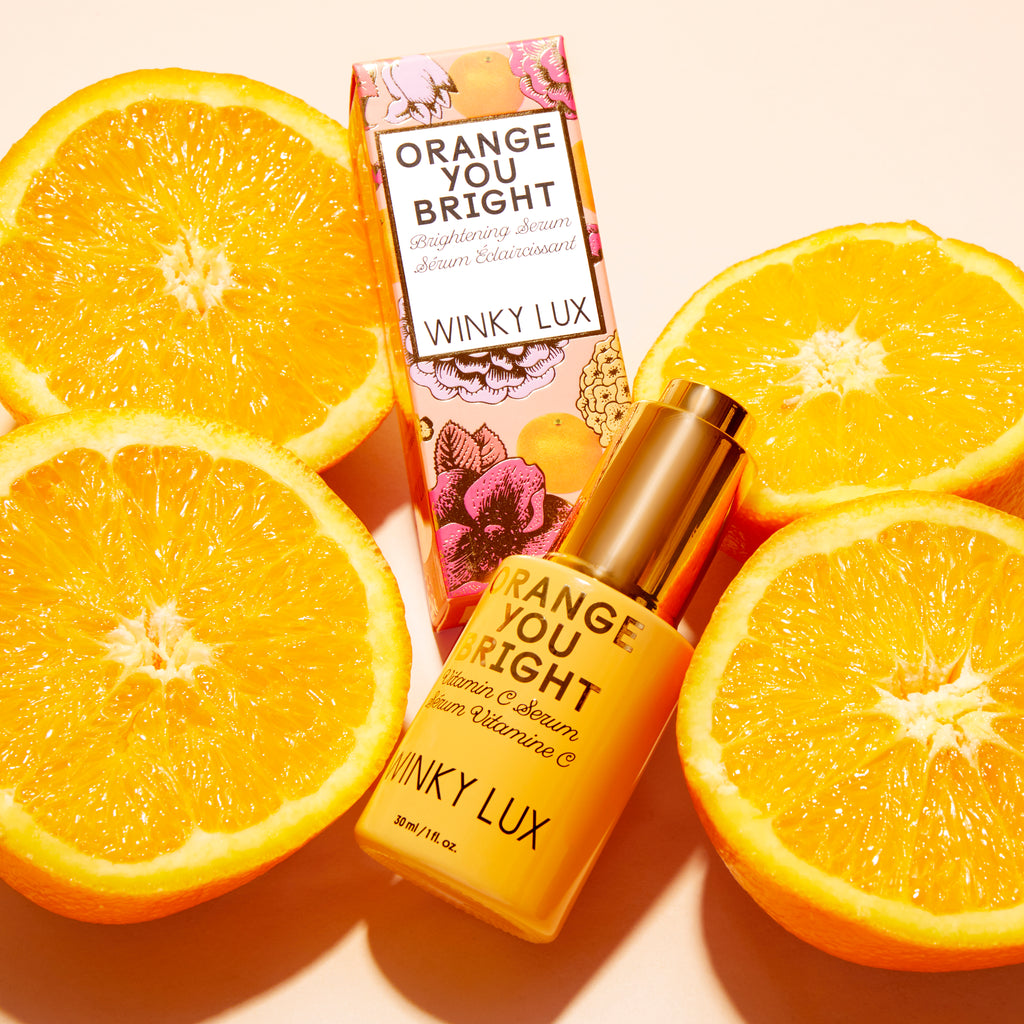 Orange you Bright Vitamin C Serum bottle and box laying in orange slices