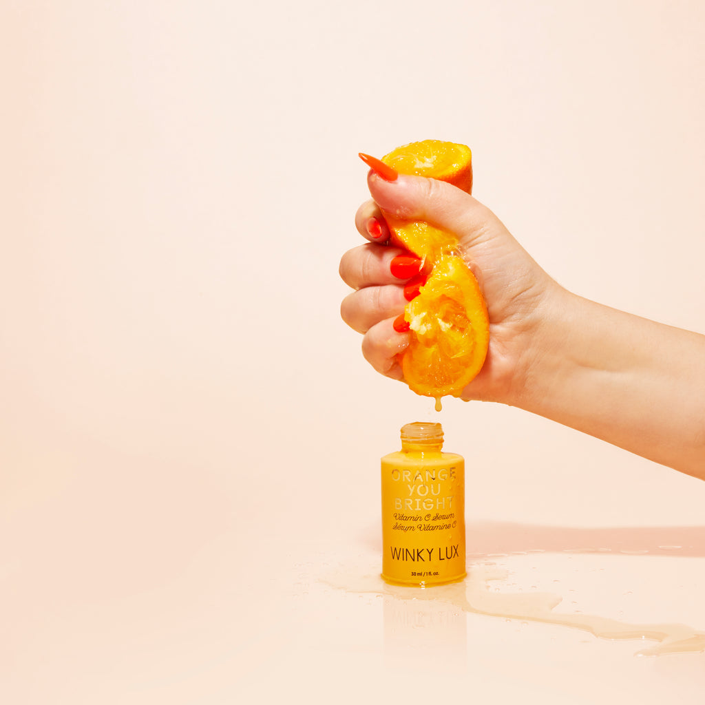 hand squeezing orange into Orange you Bright Vitamin C Serum bottle