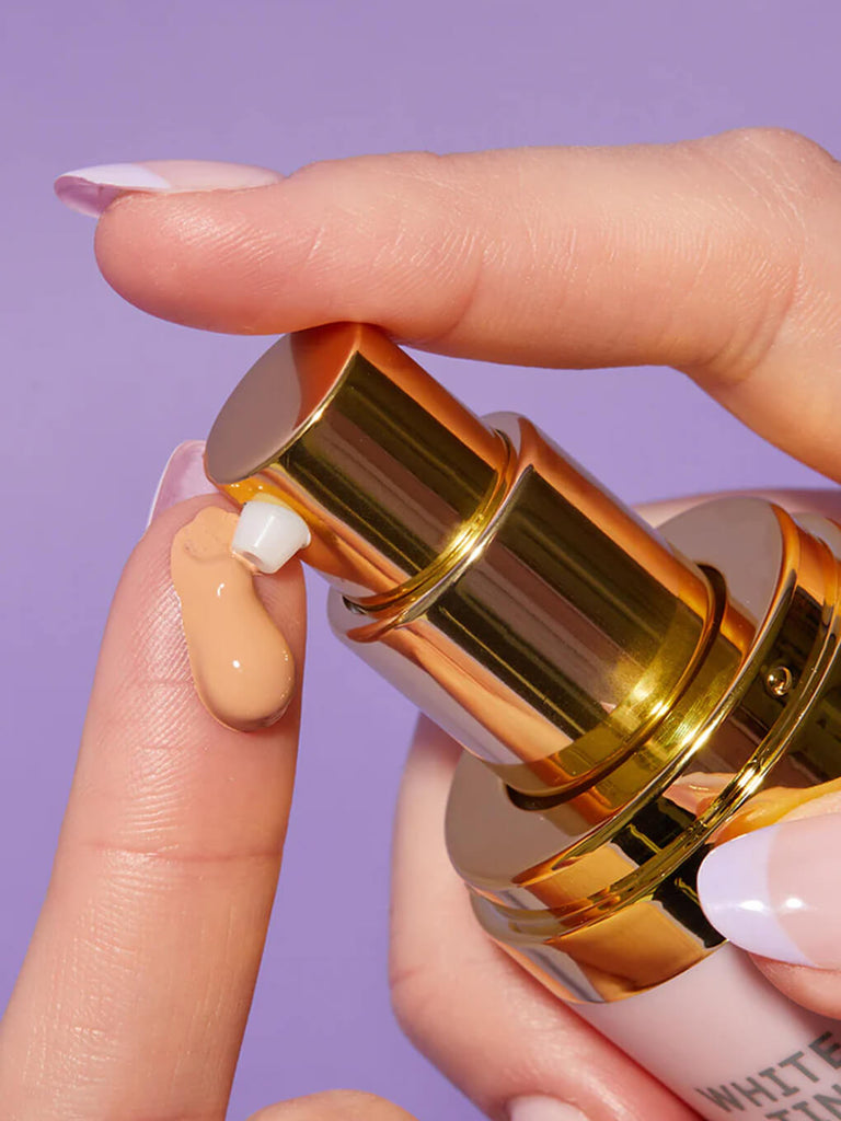 close up of finger pumping product out of tinted moisturizer bottle