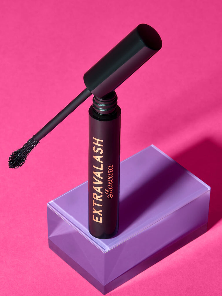 extravalash mascara component open and standing on purple surface with hot pink background