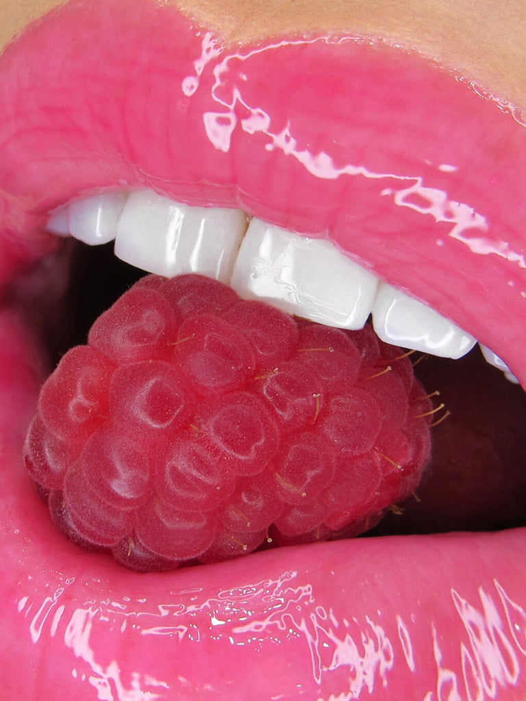 raspberry -- close up of mouth with raspberry between lips wearing ph lip gloss