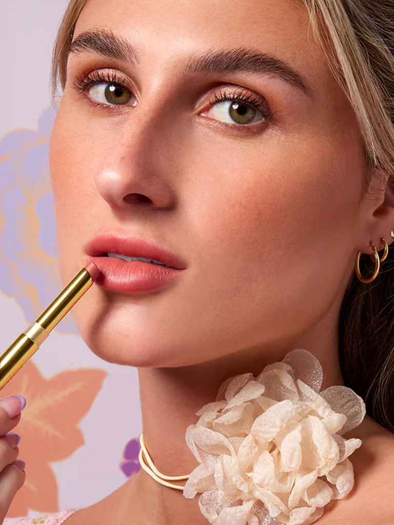 close up of blonde model applying nude skinny plump lipstick on lips
