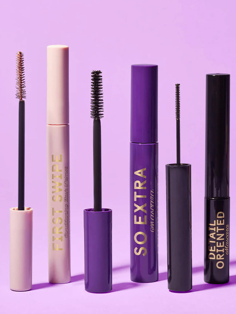 two mascaras and a lash primer standing on purple background