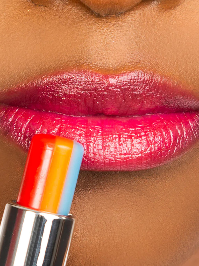 close up of model applying rainbow tinted ph lip balm on lips