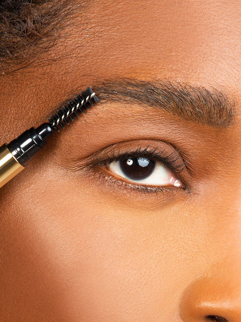 close up of model applying unibrow universal brow pencil to eyebrow with eye open