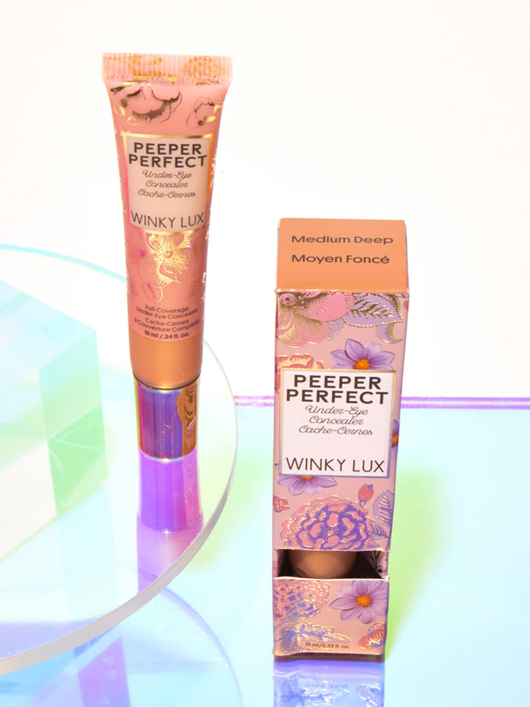 Medium/Deep -- peeper perfect under eye concealer next to box with shiny props