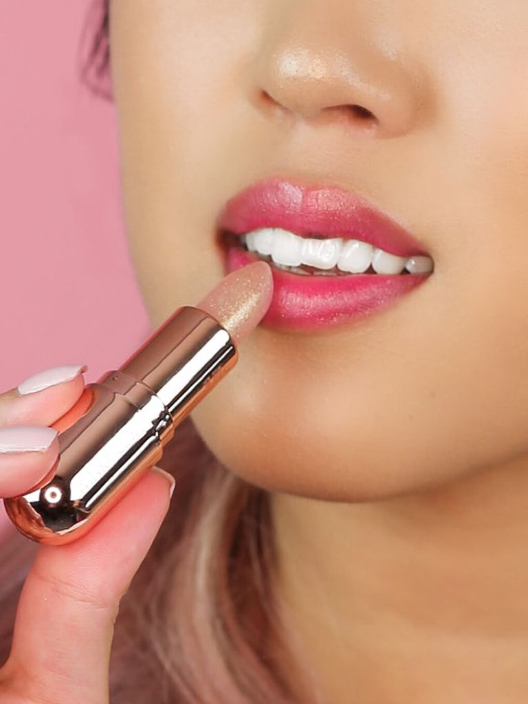 Rosé glimmer -- model applying rosé glimmer ph balm to lips on pink background